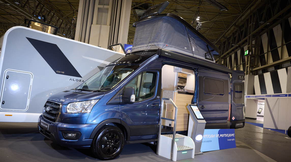 The Bailey Endeavour B65 is blue with black trim.  There is an interactive stand by the open sliding door which reveals the interior.  The pop top roof is fully open.