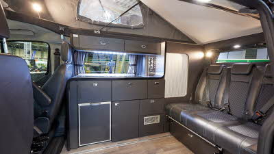 Swift Monza has black leather effect upholstery, black kitchen units and a fridge. It has a wooden effect floor and there is a sliding rail to move the rear travels seats backwards or forwards easily. The rising roof is open.