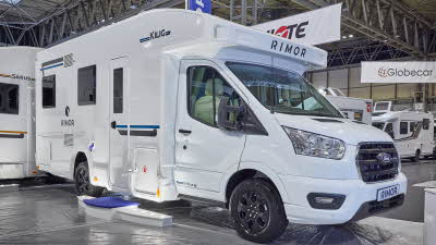 The Rimor Kilig 77 Plus is white with black and turquoise decals.  There are three white steps with a blue cover in front of the habitation door.
