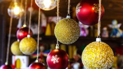 A selection of red and golden Christmas baubles hanging on the front of a market stall