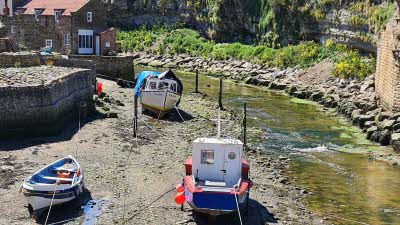 three boats rest on the riverbed at low tide