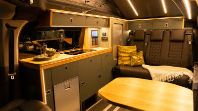 The Landseer Custom 2.0 has black upholstery with dark grey cabinets and a silver fridge.  There are two cushions on the rear seats.