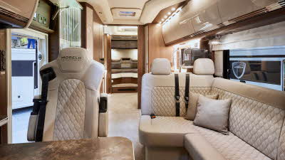 MORELO EMPIRE LINER 93LB has pale embossed upholstery showing three rear travel seats.  The floor has a cream carpet.  Towards the rear of the vehicle there is a large fixed bed.  
