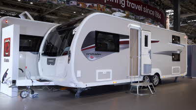 Elddis Crusader Tempest’s exterior is grey with a grey and dark red patterned decal.  The entrance door is open and there is a large metal step to gain easy access.  The roof light is open and there is a TV aerial on the roof.