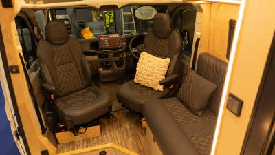The Landseer Artemis has black upholstery and has a wood floor.  The two front seats are swivelled towards the living room area. 