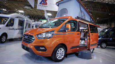 Auto-Sleeper Air exterior, the campervan is orange, the sliding door is open showing into the interior, with a step to gain easy access.   The rising roof is fully risen.