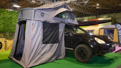 The Latitude Tents Pioneer XL is displayed on a black Porsche. It has grey canvas walls and a pale grey roof. It also has an awning.
