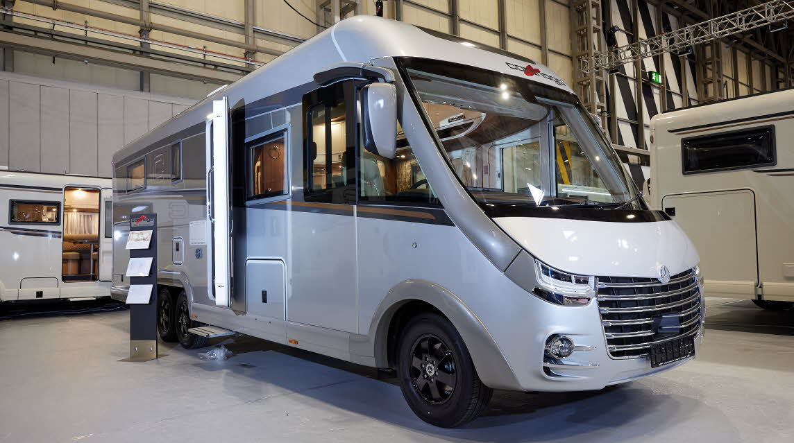 Carthago chic e-line I 64 XL QB MB has a silver exterior, its habitation door is open showing into the interior, with a step to gain easy access.  