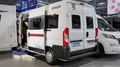 Rimor Horus 66’s exterior has white body with a red decal.  There are two windows in the rear.  Its sliding door is open and there are three steps to gain easy access.