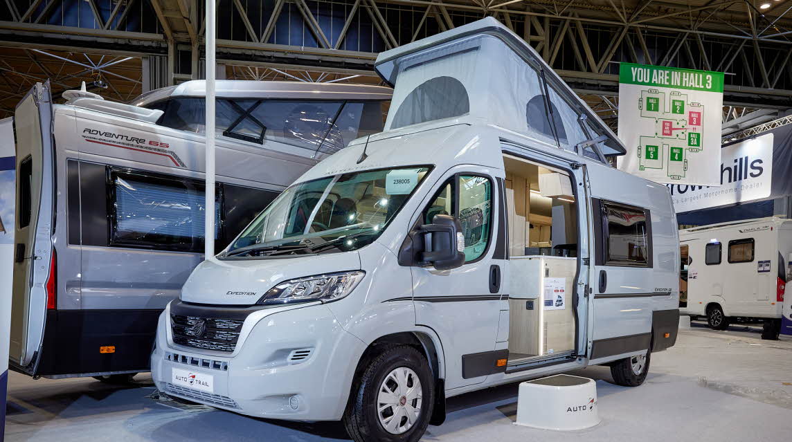 Auto-Trail Expedition 68 exterior, the van conversion is white, the sliding door is open showing into the interior, with a step to gain easy access. The rising roof is fully risen.