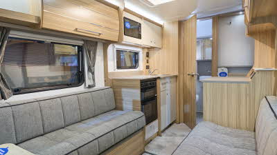 Bailey Phoenix GT75 420’s interior has pale wooden furniture with grey upholstery.  The kitchen is in the middle with a washroom to the rear.  There is a roof light above the kitchen.