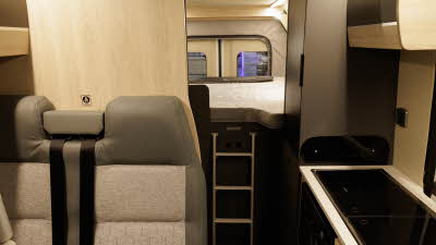 The Auto-Trail Expedition 68 has brown and beige upholstery, the kitchen is to the front right.  At the back there is a fixed rear bed with a ladder to gain easy access.