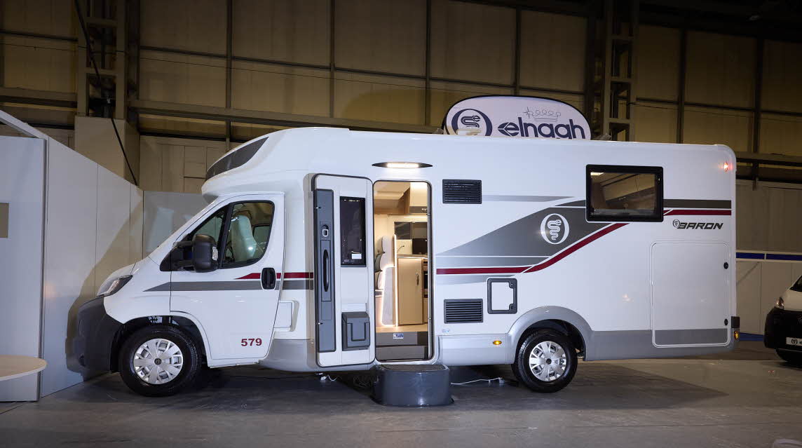 The Elnagh Baron 579 is white with grey and dark red decals.  There is a black step by the open habitation door, revealing the interior.