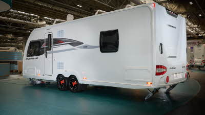 Swift Challenger Exclusive 650's exterior is white with grey and red graphics.  The caravan is a twin axle and has its corner steadies down.
