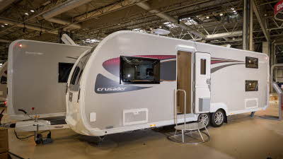 Elddis Crusader Tempest exterior is grey and white with black and red decals.  The door is open and there is a metal step to gain easy access to the interior.