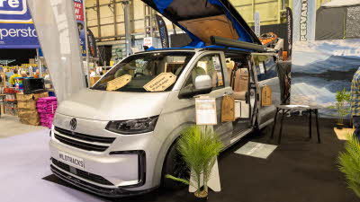 The Wildtracks Campervans Explorer has a light grey exterior, its rising roof is open with a blue lining. Its sliding door is also open.