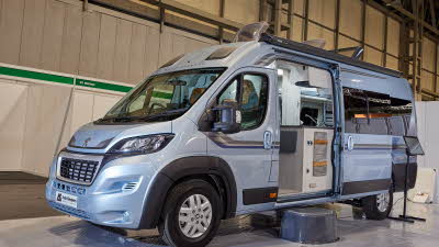 Auto-Sleeper Warwick XL exterior, the motorhome is pale blue, the sliding door is open showing into the interior, with a step to gain easy access.  The three roof lights are fully open.
