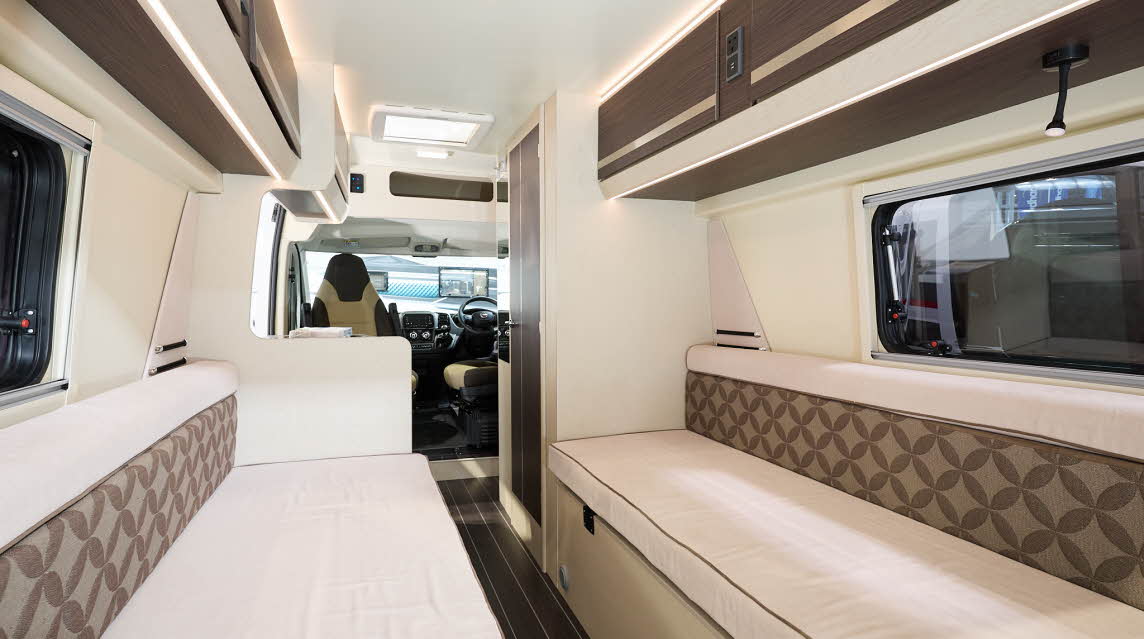Rimor Horus 66’s interior has cream upholstery with brown patterned inserts.  Its furniture is pale wood with dark wood inserts.  It has a wood effect floor.  The two front seat are swivelled.  It has a central skylight. 