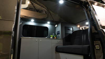 The AURA 4 Tend has black upholstery with matt grey walls and white cabinets.  There are two plants on the kitchen worksurface, it's roof is open..