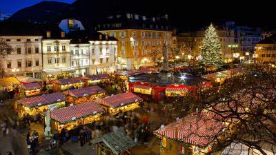 An elevated view of Christmas market stalls and a large tree set in the square at Bolzano Italy