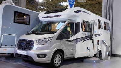 Bailey Adamo 75-4T exterior, the vehicle has a silver cab with the body being predominantly whte, the habitation door is open showing into the interior, with a step to gain easy access.  There is an interactive tablet on a pedestal outside.  