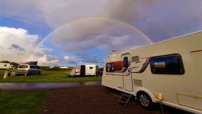Caravan on pitch under a rainbow at Willingcott Club Campsite