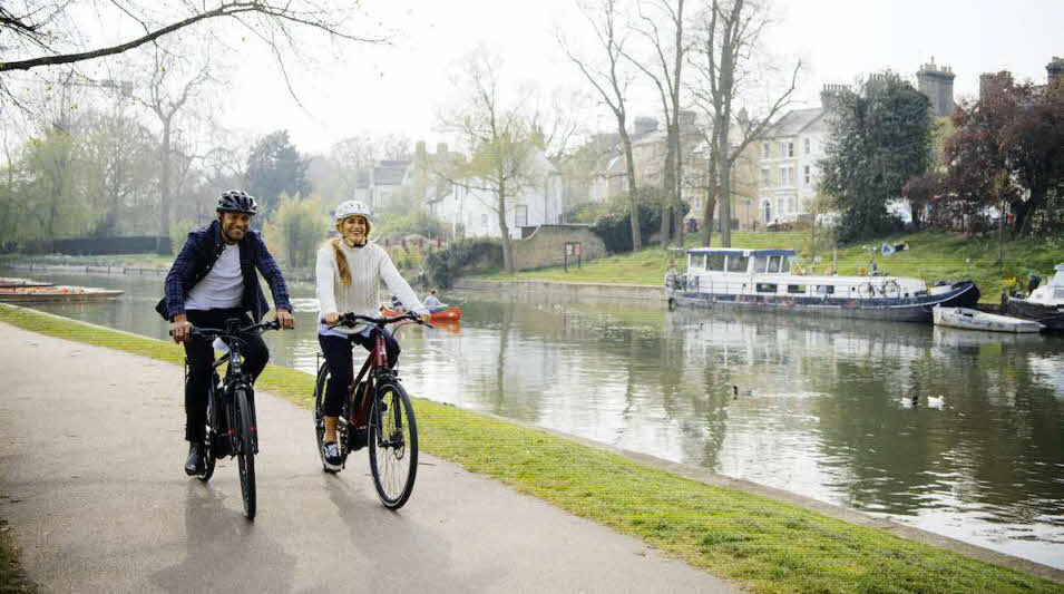 Couple riding electric bikes by the river