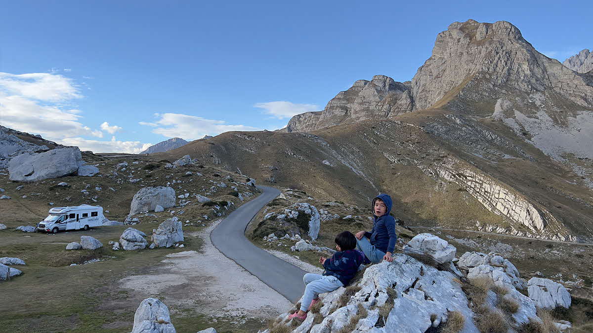 Marcus Leech's children sit on a rock looking out at the Big European Odyssey motorhome and Montenegro's mountains