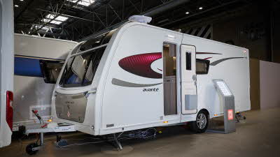 Elddis Avante 454 exterior is white with black and red decals.  There is an interactive display stand leaning against the caravan.