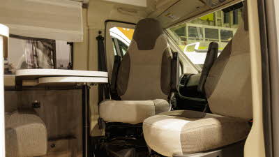 The Benimar Benivan 144 has two tone brown upholstery.  The front driving seats are swivelled to face the white table.  The table can be extended.