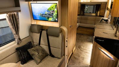 The Bailey Autograph 81-5 has two tone brown upholstery with wooden furniture.  There is a TV above the rear passengers' seats.  Its kitchen is to the right with a rear lounge.