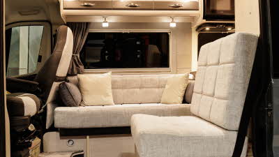 The Auto-Sleeper Symbol has pale upholstery and there are four cushions on the inner sofa.  The microwave is in the top right.