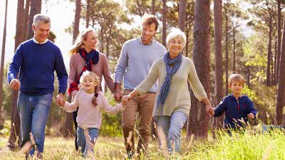 a family with grandparents, parents and two small children walking together in the woods