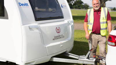 Man in high vis stood next to caravan a frame