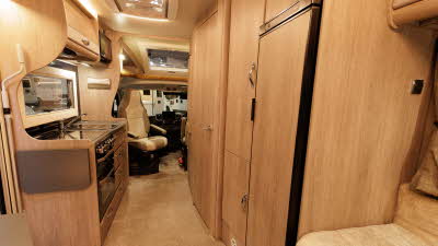 The Auto-Sleeper Broadway EL has wooden furniture, the kitchen is towards the front with a full size fridge to the left.  The passenger's front seat is swivelled to face the motorhome.