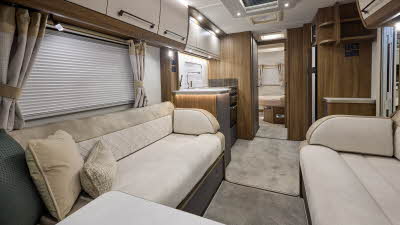 Interior of the Buccaneer Skylinder Commodore with cream sofas edged with suede effect material. The rear bedroom door is open revealing the fixed island bed.  The large roof light will let natural light flood in.