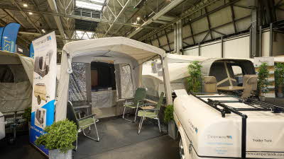 Campmaster AIR 600 LX exterior, cream and brown canvas.  There are four lime green canvas chairs.  The travelling trailer is shown in cream 