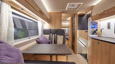 Auto-Trail Frontier Scout has two tone upholstery, with wooden furniture.  The floor has beige carpet.  The overhead lockers are cream with wooden surrounds.  There is an extractor fan in the middle of the vehicle.  
