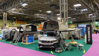 Dometic TRT 140 AIR roof tent is green with a khaki roof.  It is shown on a silver car and has a living area under the tent's canopy.