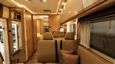 The MORELO PALACE 90M has brown leather upholstery with cream and wooden furniture.  There are two cushions on the travelling seats.  