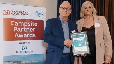 A Caravan and Motorhome Overseas Campsites Award Runner Up with the Chairman next to a sign showing Campsite Partner Awards, with Irish Ferries below it