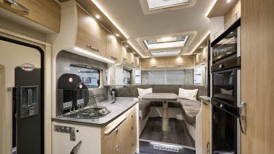 Frankia I 7400 PLUS Platin Pure Edition’s interior has wooden furniture with white surrounds.  There are three skylights.  The kitchen is central with the hob on the left and the fridge freezer on the right.  There is a u-shaped lounge to the rear.