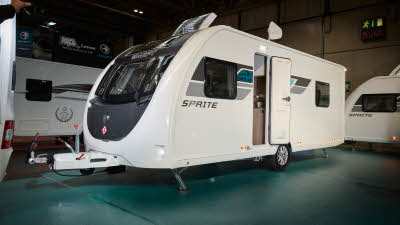 Swift Sprite Grande Quattro FB has a white exterior with grey and turquoise graphics, it has a black panel under the front window and its skylight is open.  It has a single axle.