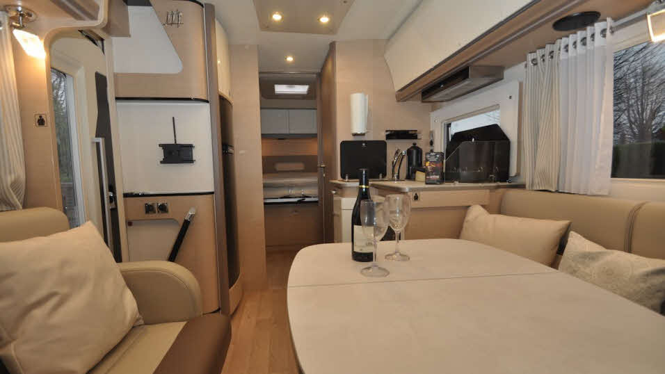 Spacious M96 motorhome interior with table, seating, kitchen and storage