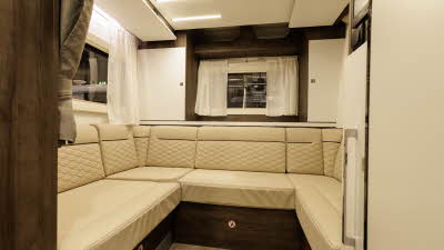 The Benimar Primero 282 has cream upholstery which is complemented with dark wooden furniture.  The kitchen is to the right and towards the rear, there is an end lounge.