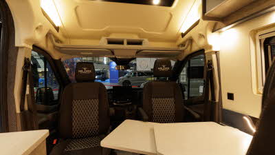 WildAx Motorhomes Equinox has brown upholstery, the front two seats are swivelled to face the interior and there is a white extendable table.