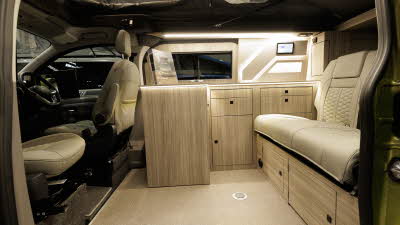 The Hillside Leisure Birchover Classic is in Warm Green, its rising roof and doors are closed.The Hillside Leisure Birchover Classic has cream upholstery and its cabinets are made from light wood.  Its rising roof is open.