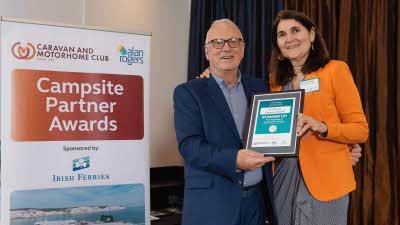 A Caravan and Motorhome Overseas Campsites Award Runner Up with the Chairman next to a sign showing Campsite Partner Awards, with Irish Ferries below it