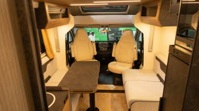 The Rimor Sarus Plus 66 has coffee and cream upholstery complemented by wooden furniture.  The front seats are swivelled to face the rest of the van.  There is a table in the dining area which is folded.