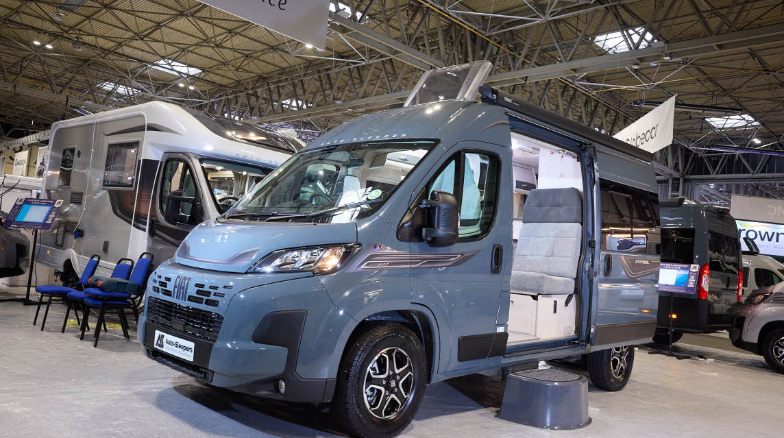 The Auto-Sleeper Symbol has a grey exterior.  There is a black step by the opening sliding door which reveals the rear passenger seats.